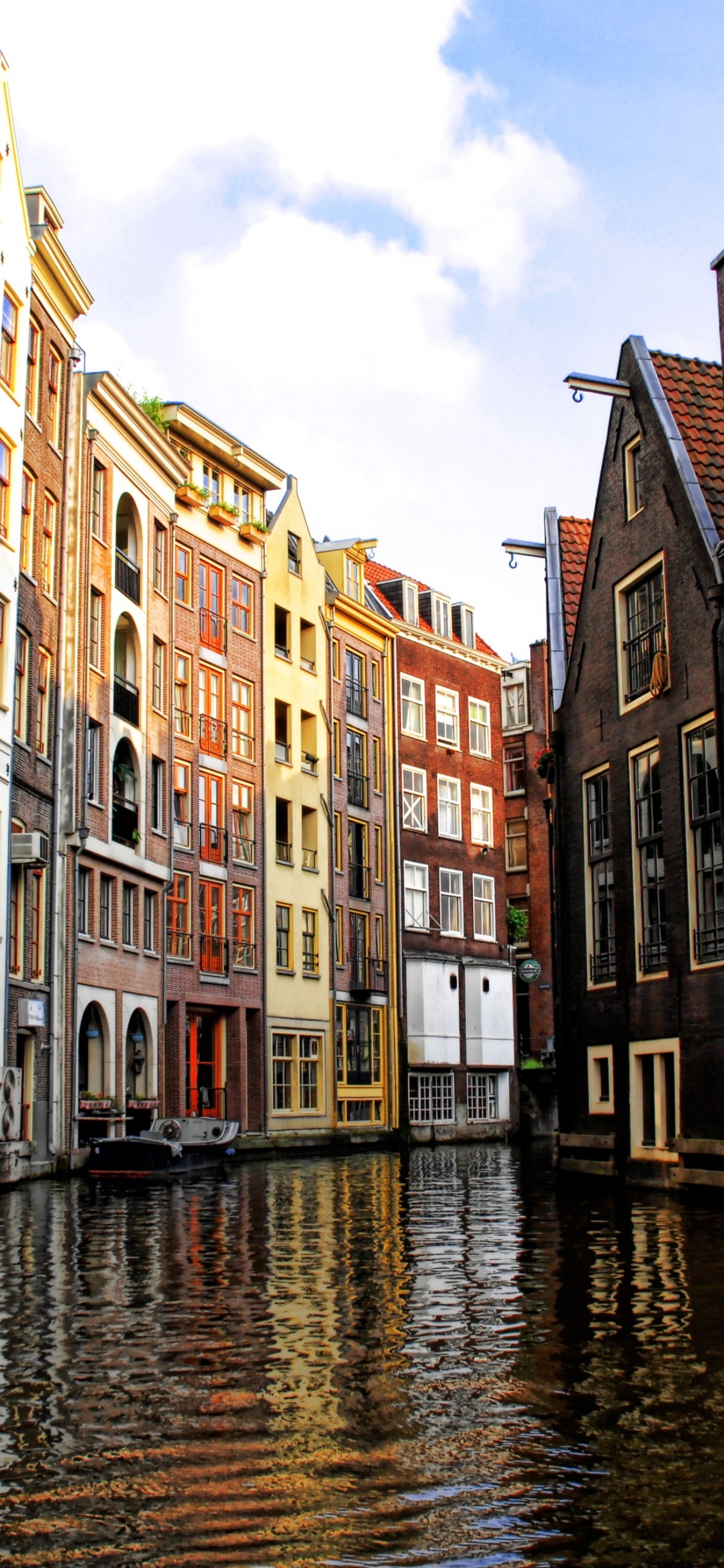 Brown Concrete Building Beside River Under Blue Sky During Daytime. Wallpaper in 1125x2436 Resolution