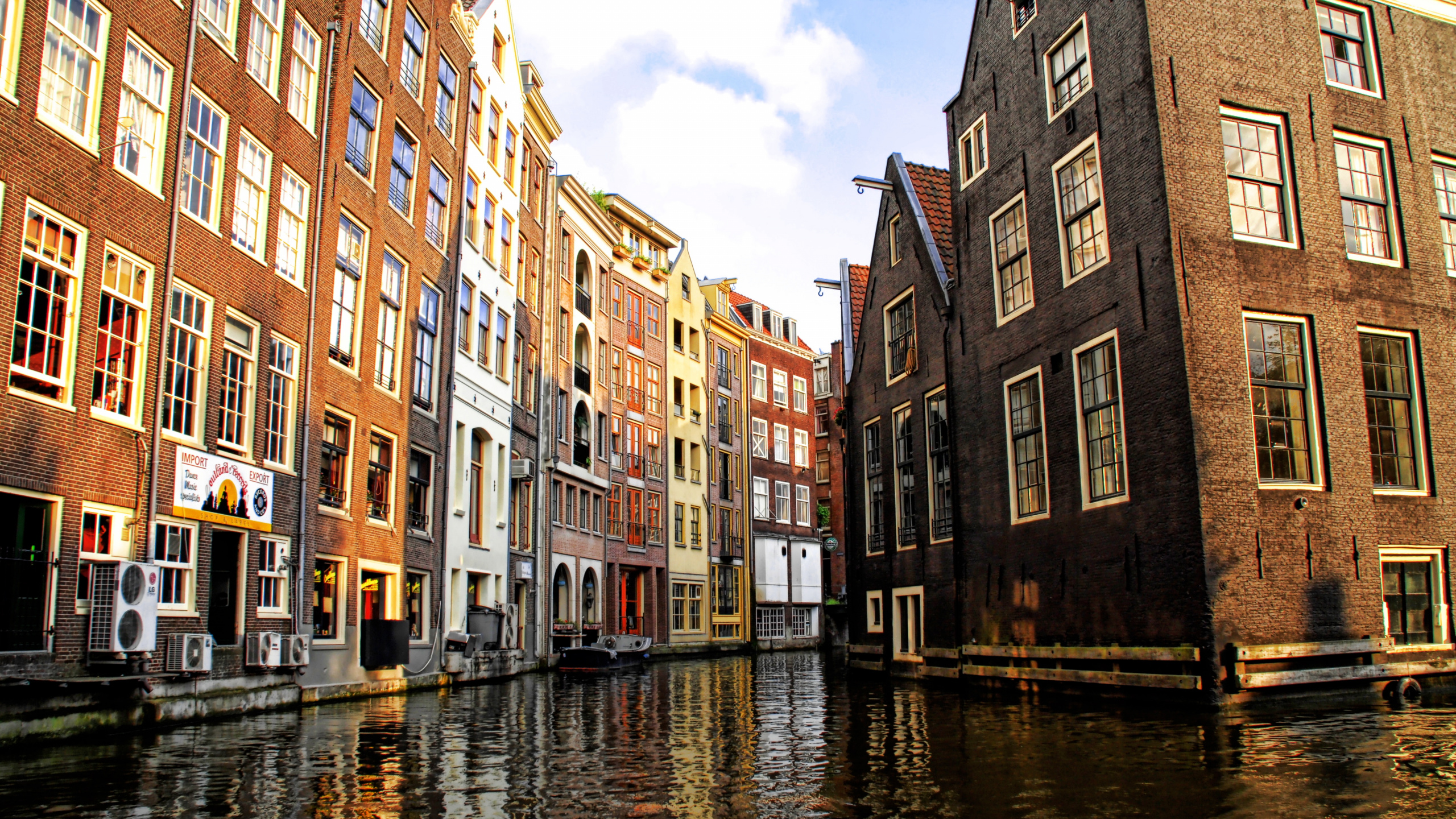 Brown Concrete Building Beside River Under Blue Sky During Daytime. Wallpaper in 2560x1440 Resolution