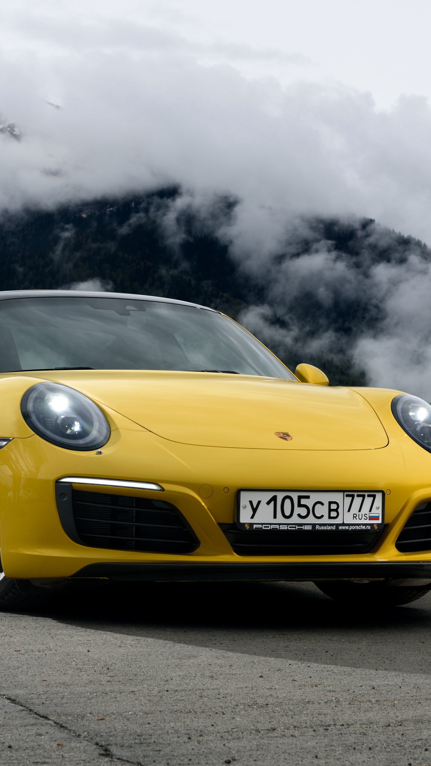 Yellow Porsche 911 on Black Asphalt Road Under Gray Clouds. Wallpaper in 1440x2560 Resolution