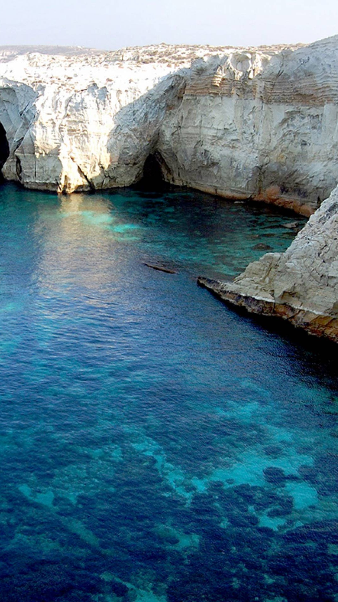 Brauner Felsiger Berg Neben Blauem Meer Tagsüber. Wallpaper in 1080x1920 Resolution