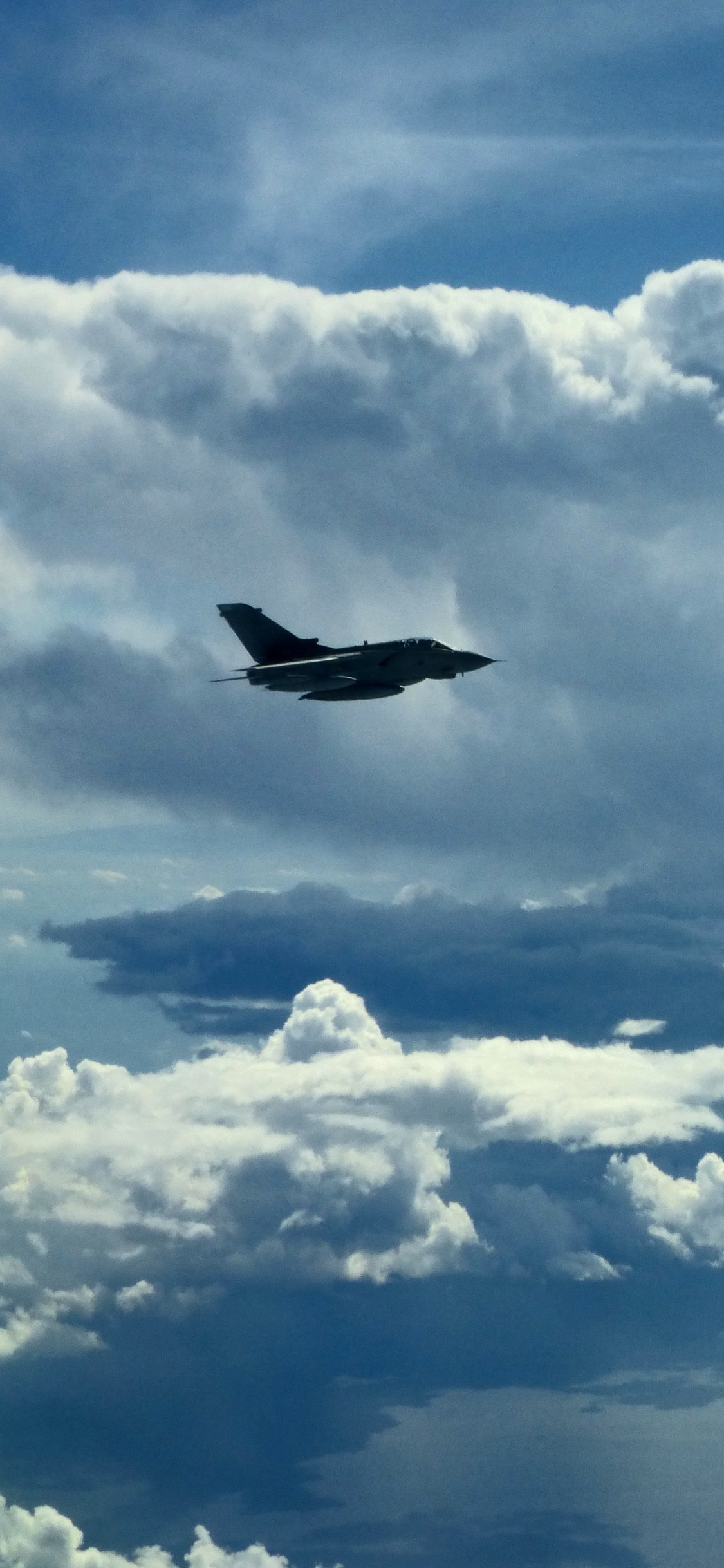 Black Airplane Flying Under White Clouds During Daytime. Wallpaper in 1125x2436 Resolution