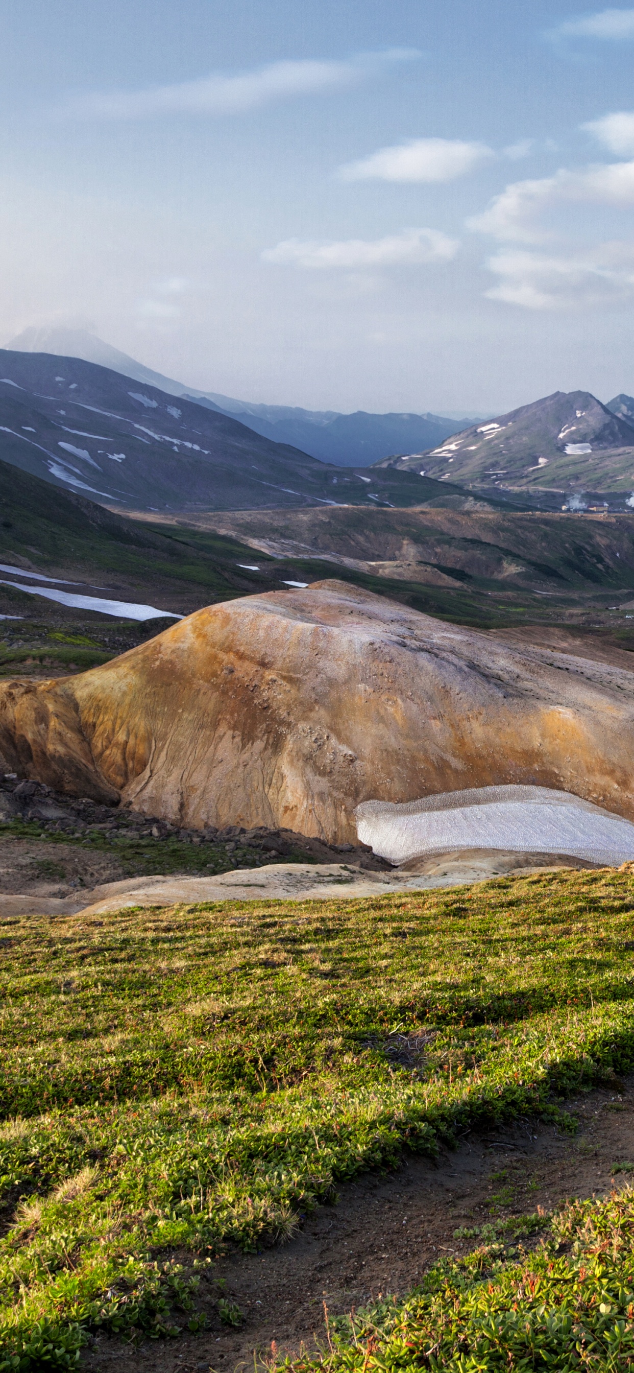 Green Grass Field Near Brown Mountain Under White Clouds During Daytime. Wallpaper in 1242x2688 Resolution