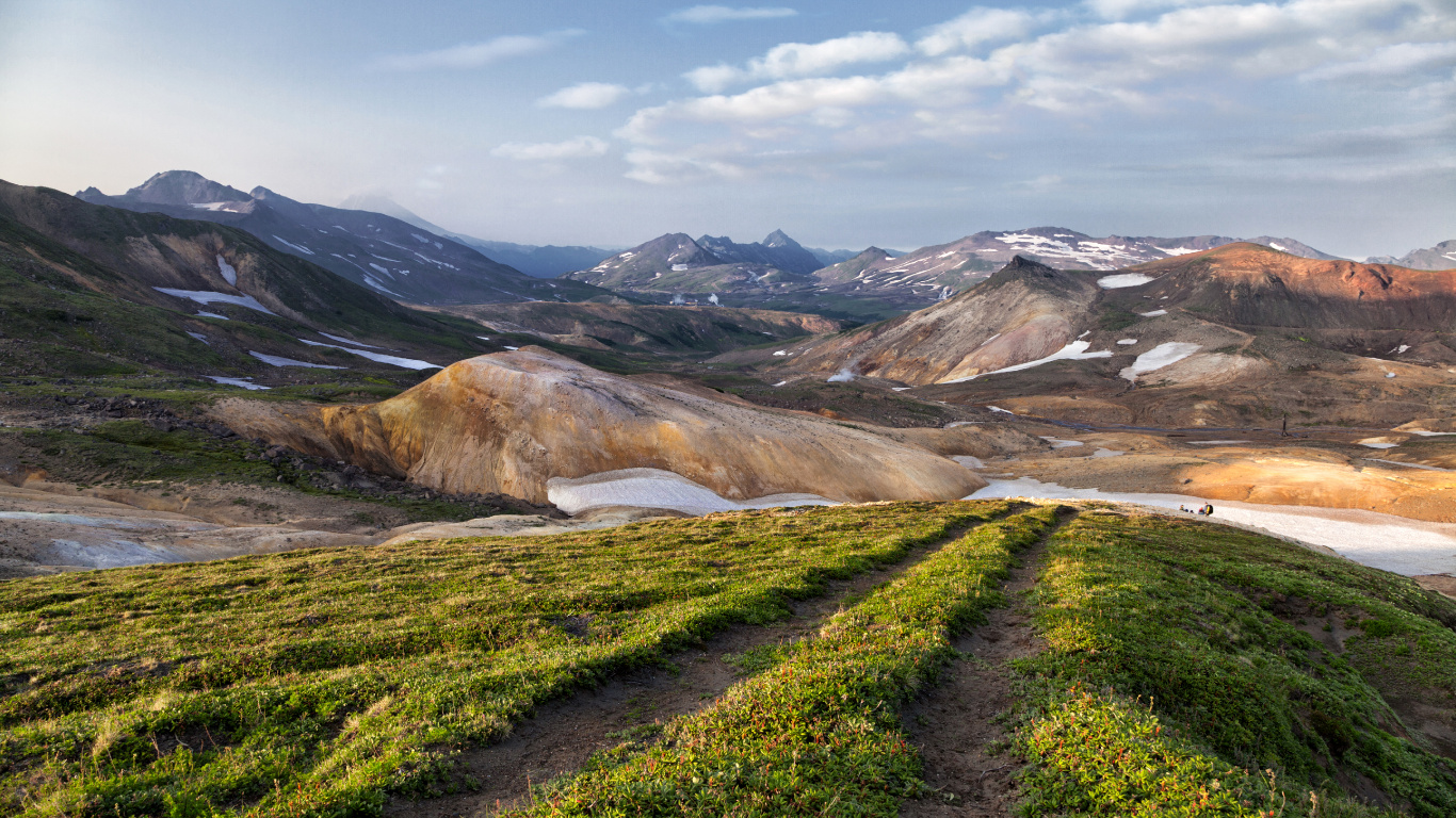 Green Grass Field Near Brown Mountain Under White Clouds During Daytime. Wallpaper in 1366x768 Resolution