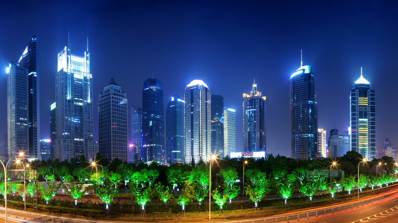 Green Trees Near High Rise Buildings During Night Time. Wallpaper in 1366x768 Resolution