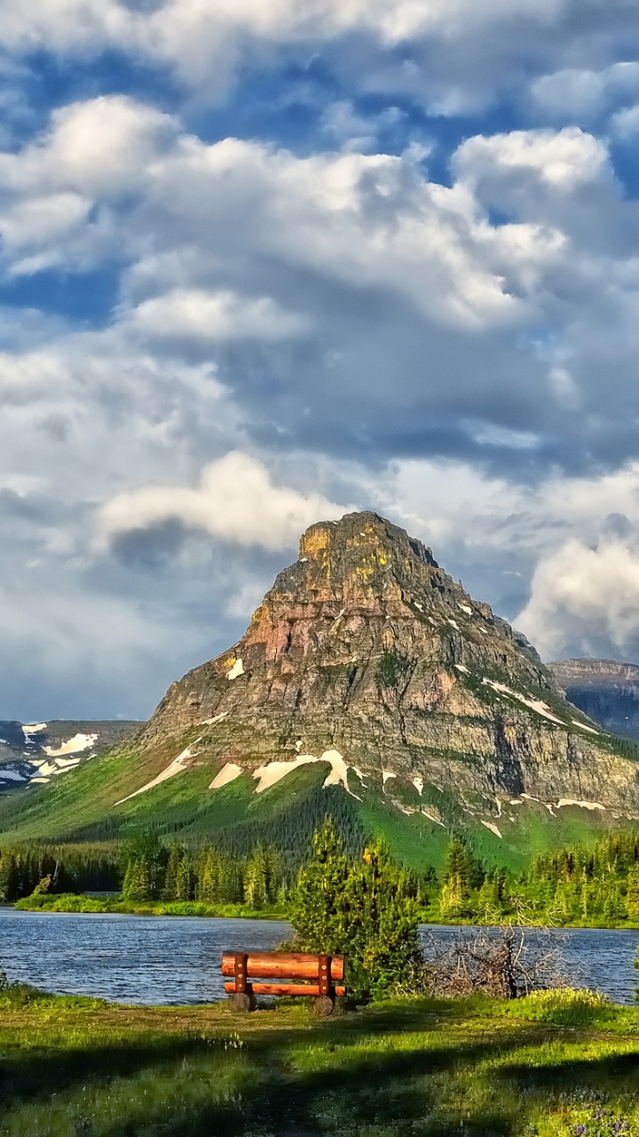 Brown Wooden Bench on Green Grass Field Near Lake and Mountain Under White Clouds and Blue. Wallpaper in 720x1280 Resolution