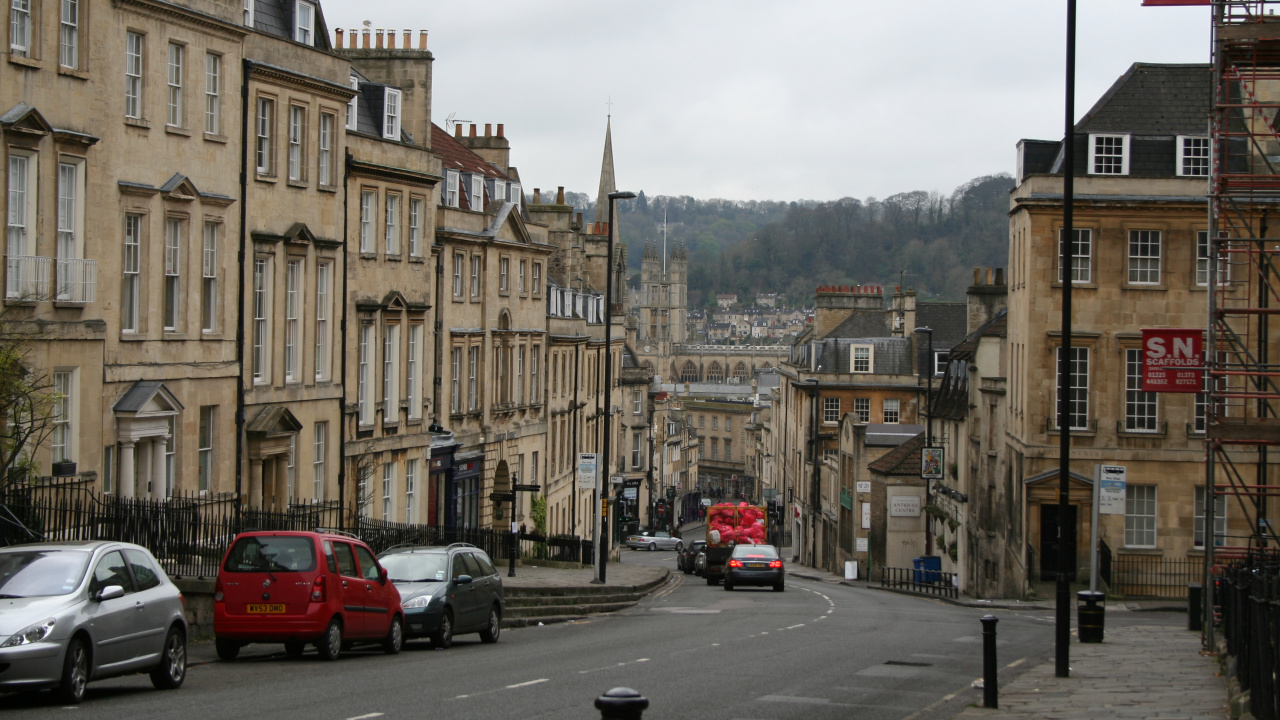 Voiture Rouge Sur Route Près D'un Bâtiment en Béton Brun Pendant la Journée. Wallpaper in 1280x720 Resolution