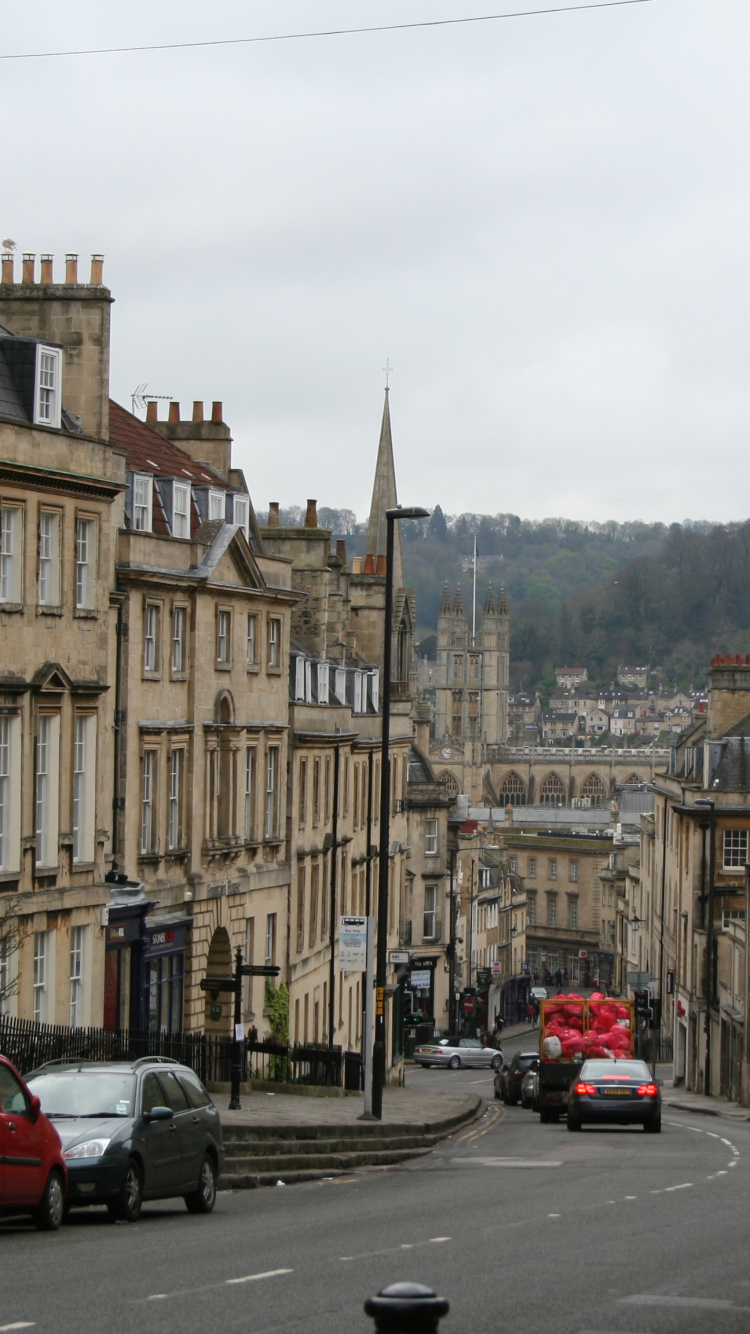 Voiture Rouge Sur Route Près D'un Bâtiment en Béton Brun Pendant la Journée. Wallpaper in 750x1334 Resolution