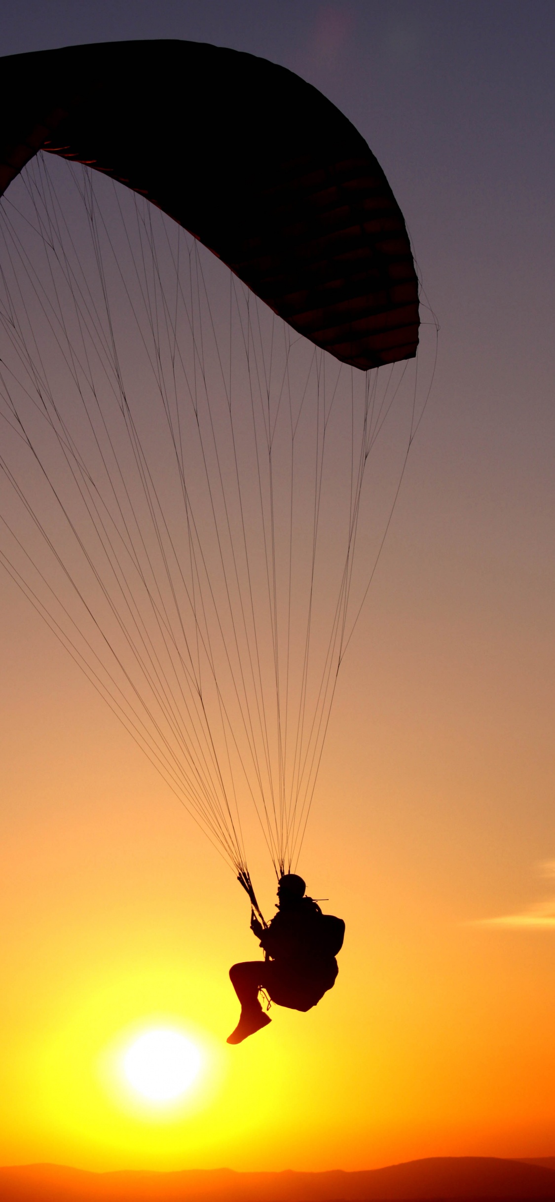 Silhouette de Personne Équitation Parachute Pendant le Coucher du Soleil. Wallpaper in 1125x2436 Resolution