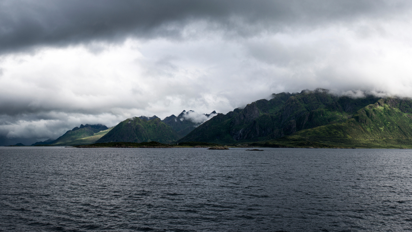 Green Mountain Beside Body of Water Under Cloudy Sky During Daytime. Wallpaper in 1366x768 Resolution