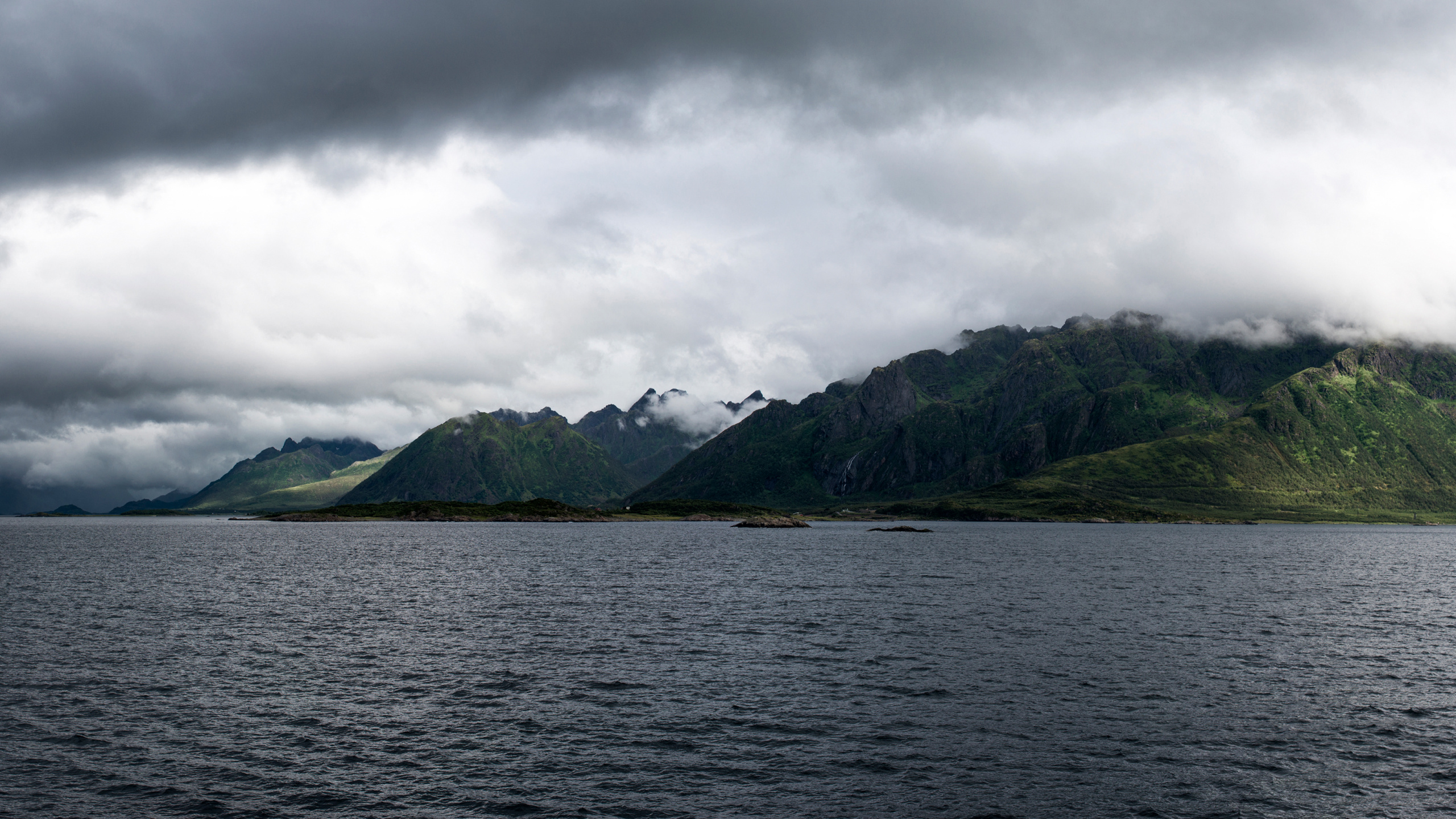 Green Mountain Beside Body of Water Under Cloudy Sky During Daytime. Wallpaper in 2560x1440 Resolution