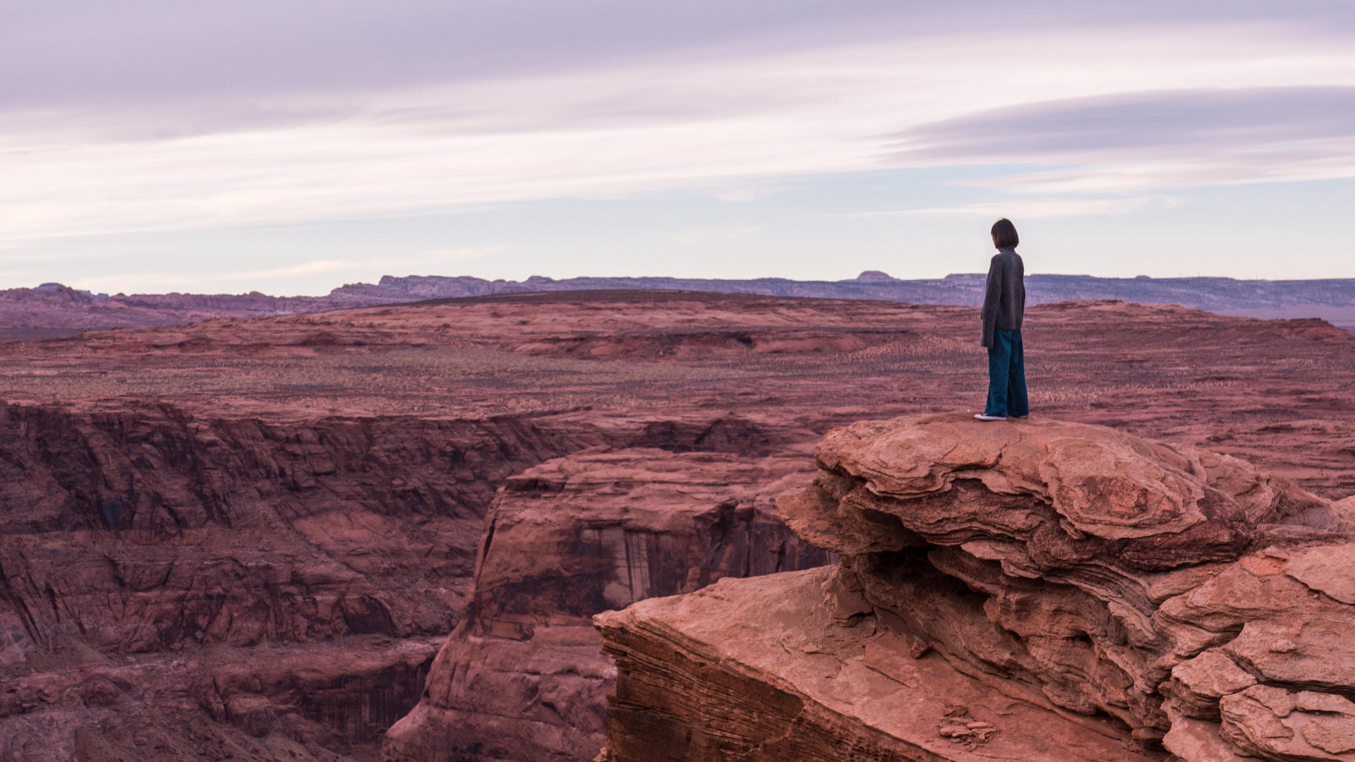 Man in Blue Jacket Standing on Brown Rock Formation During Daytime. Wallpaper in 1920x1080 Resolution