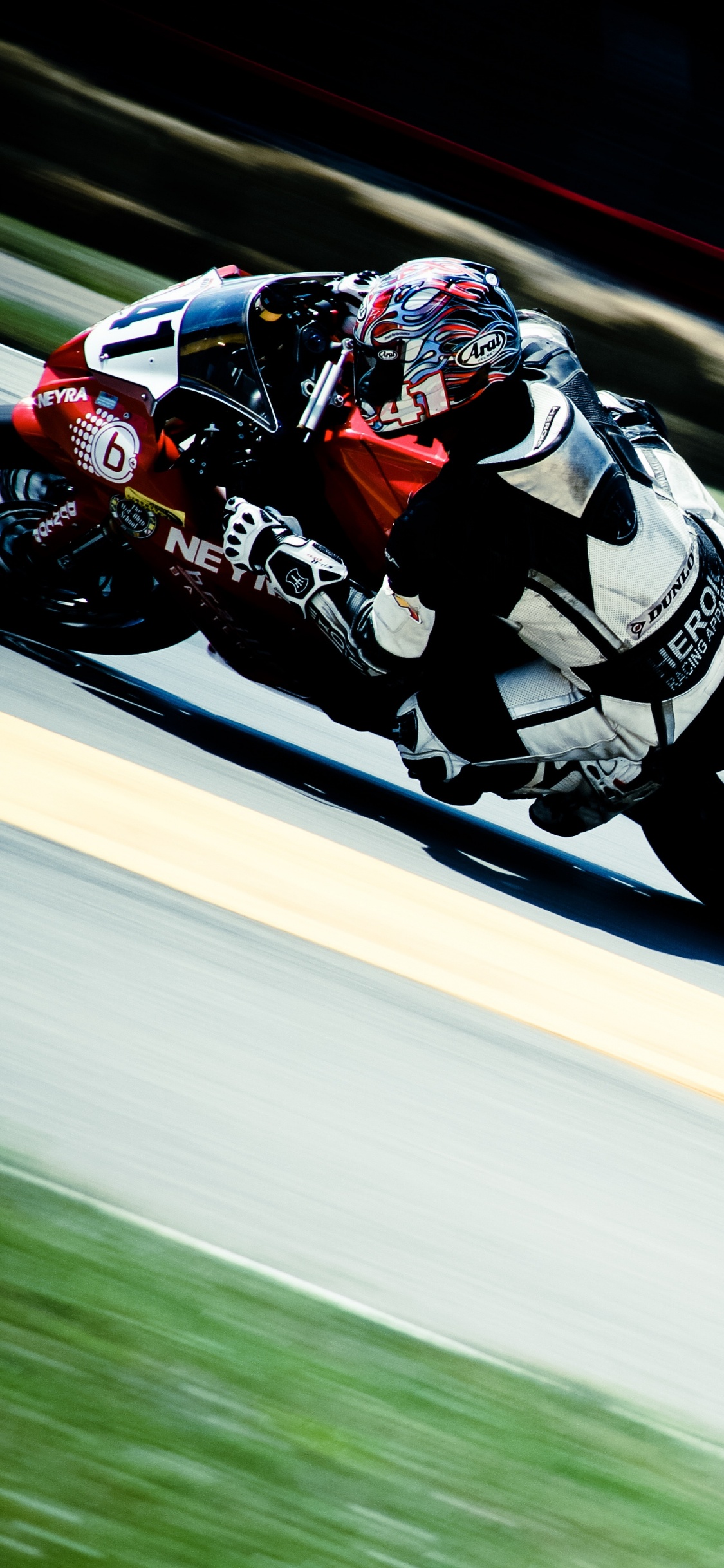 Man in Red and White Racing Suit Riding on Sports Bike. Wallpaper in 1125x2436 Resolution