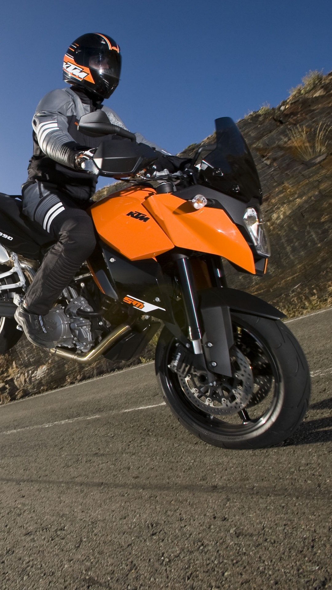 Hombre en Casco de Motocicleta Naranja y Negro Montando Bicicleta Deportiva Naranja y Negra Sobre Asfalto Gris. Wallpaper in 1080x1920 Resolution