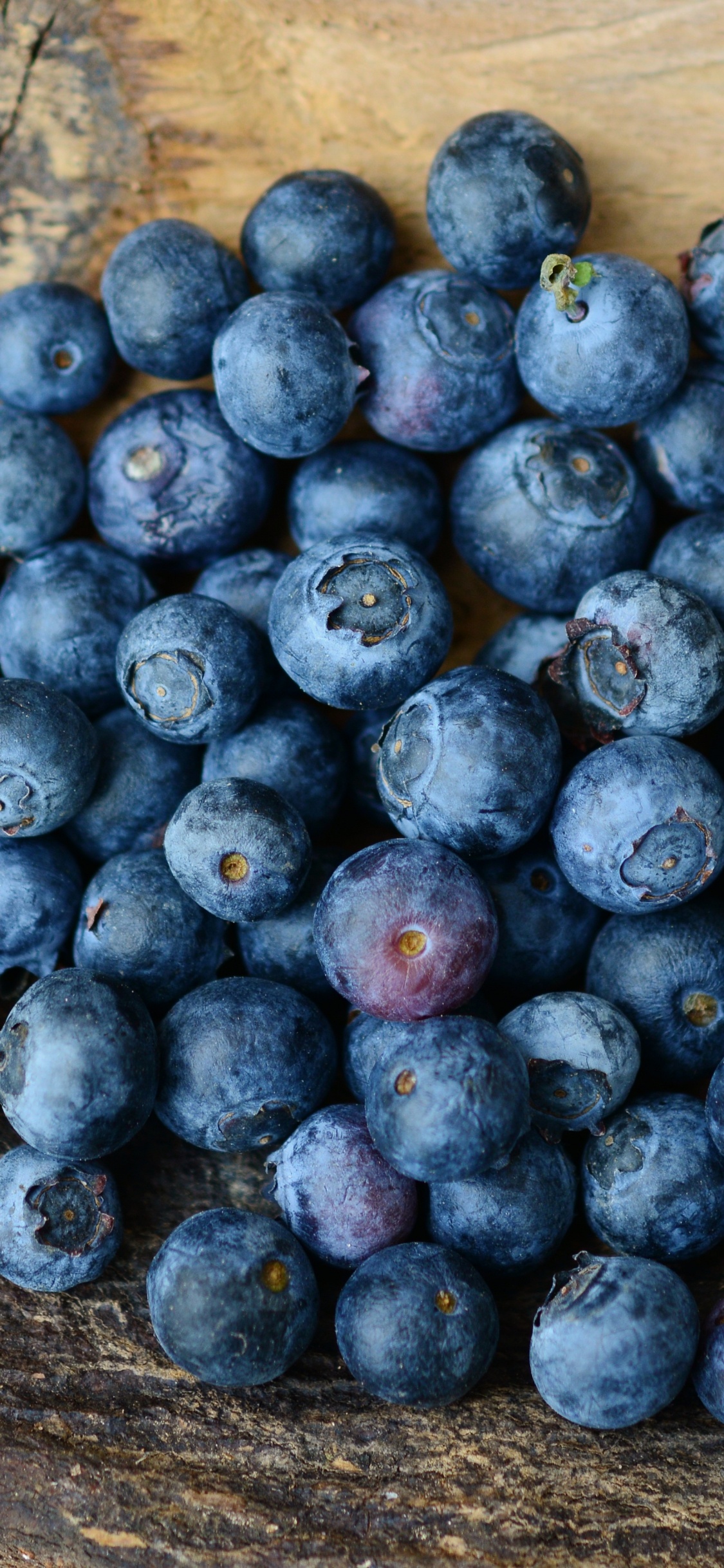 Baies Bleues Sur Une Surface en Bois Marron. Wallpaper in 1125x2436 Resolution