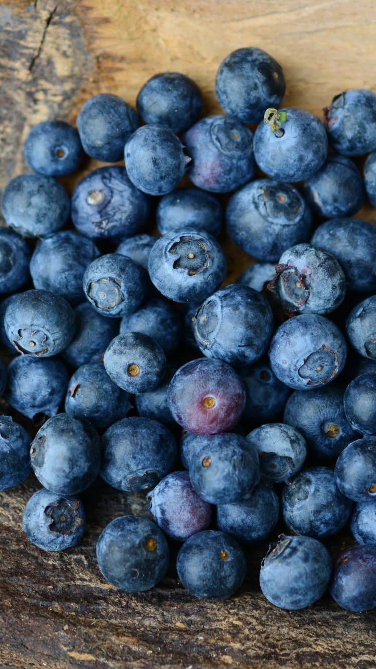 Baies Bleues Sur Une Surface en Bois Marron. Wallpaper in 750x1334 Resolution