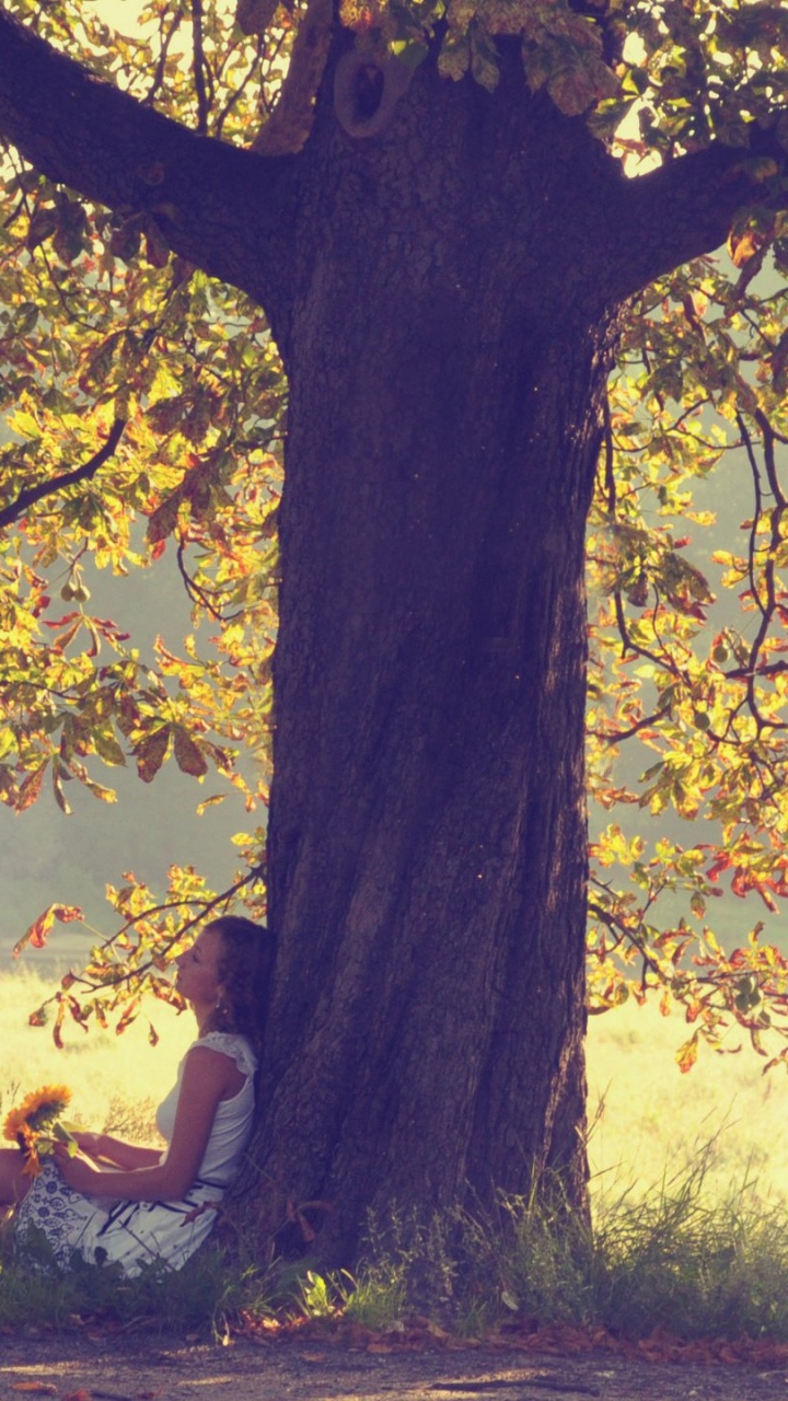 Femme en Débardeur Blanc Assis Sur un Terrain D'herbe Verte Près D'un Plan D'eau Pendant la Journée. Wallpaper in 720x1280 Resolution