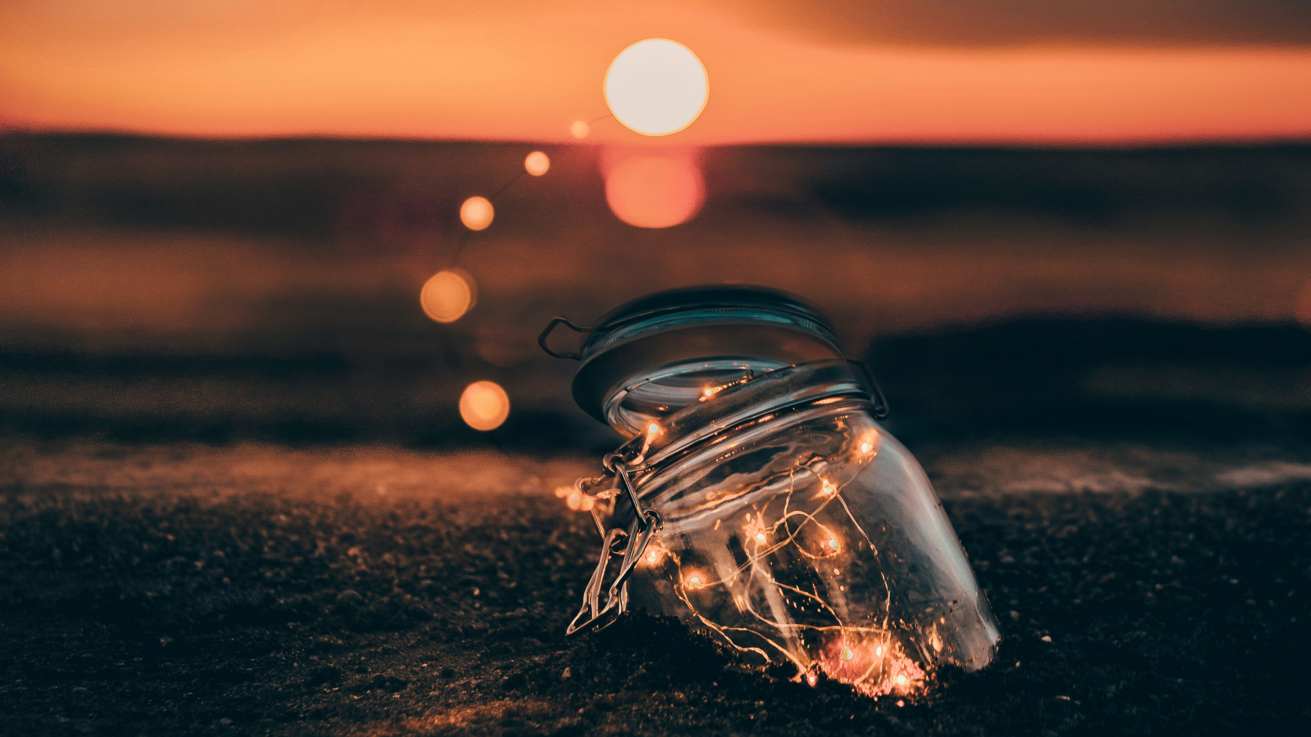 Clear Glass Container on Brown Sand During Sunset. Wallpaper in 2560x1440 Resolution