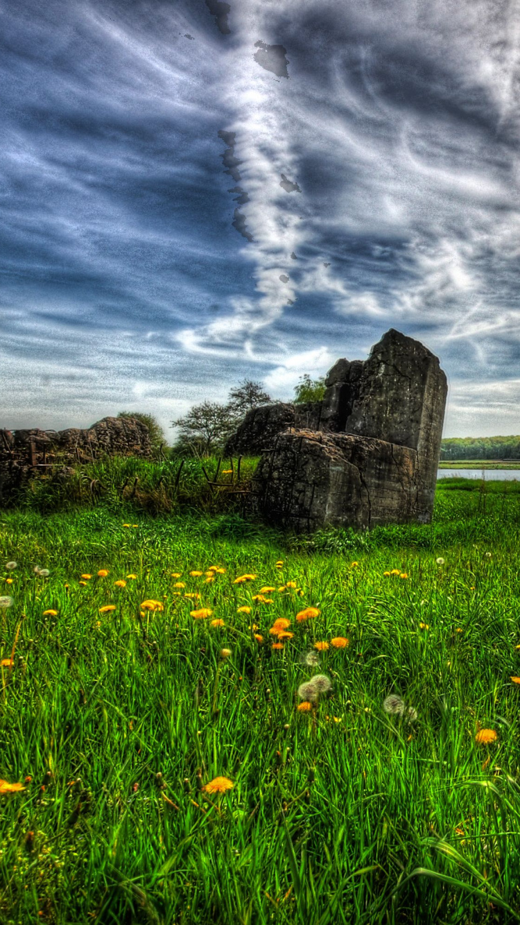 Campo de Hierba Verde Cerca de la Formación Rocosa Marrón Bajo Las Nubes Blancas y el Cielo Azul Durante el Día. Wallpaper in 750x1334 Resolution