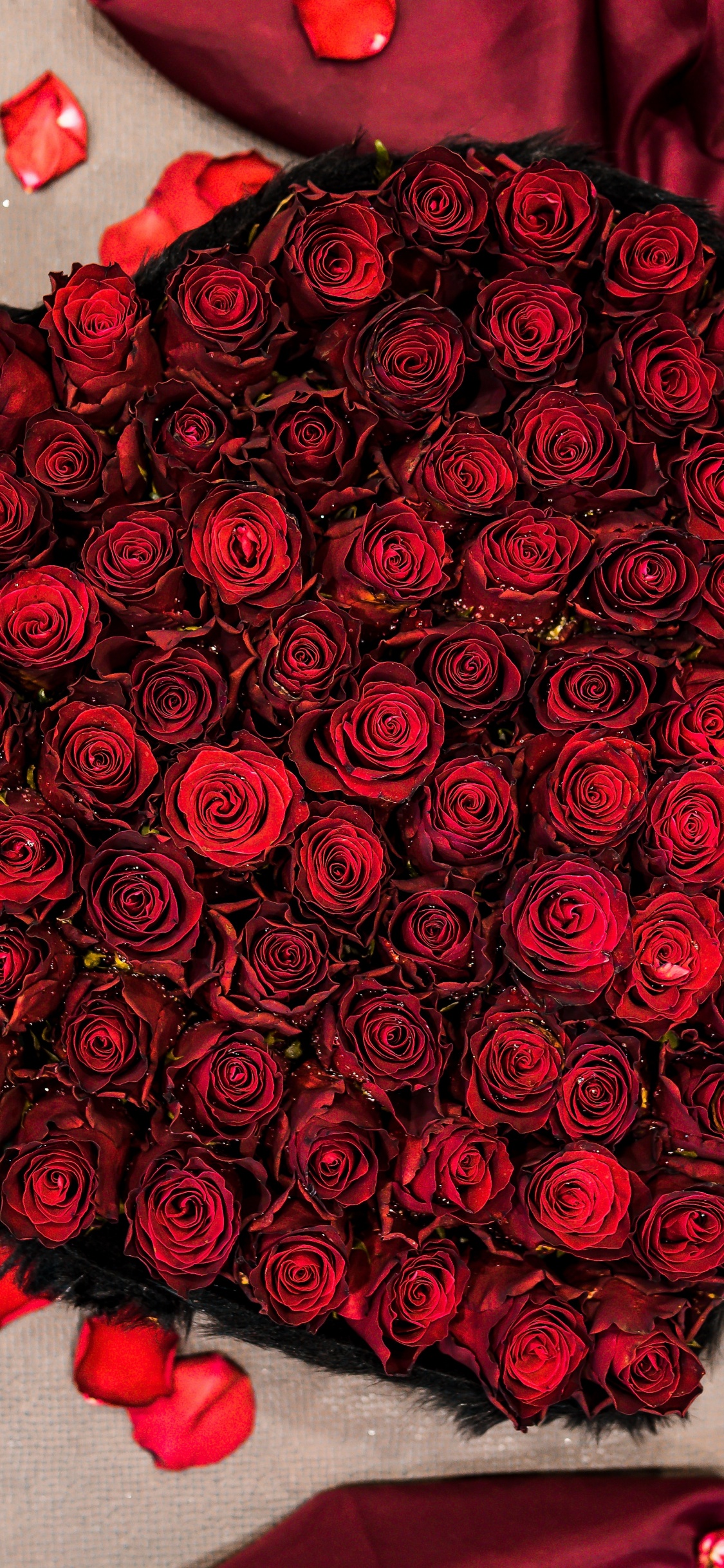 Roter Rosenstrauß Auf Weißem Und Rotem Textil. Wallpaper in 1125x2436 Resolution