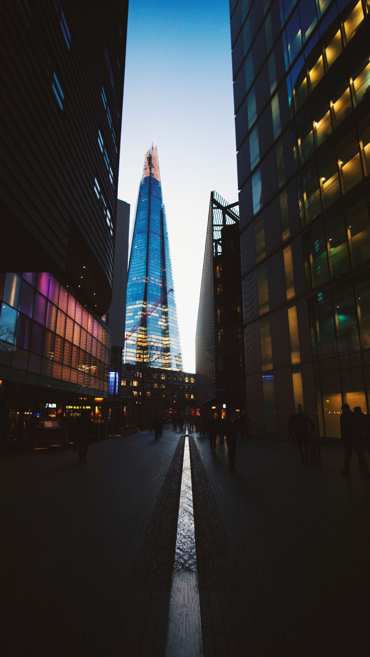 Gente Caminando en la Calle Cerca de un Edificio de Gran Altura Durante la Noche. Wallpaper in 720x1280 Resolution