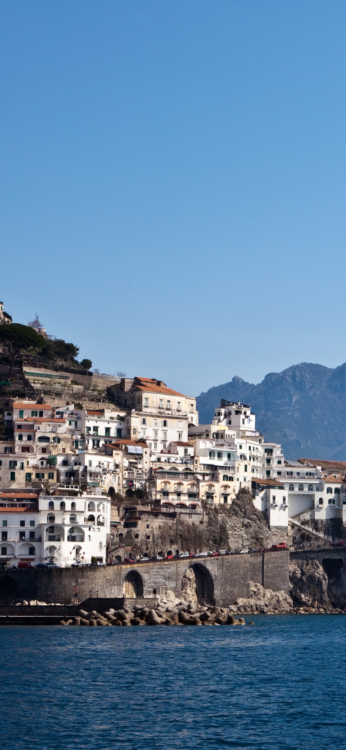 White and Brown Concrete Building Near Body of Water During Daytime. Wallpaper in 1125x2436 Resolution