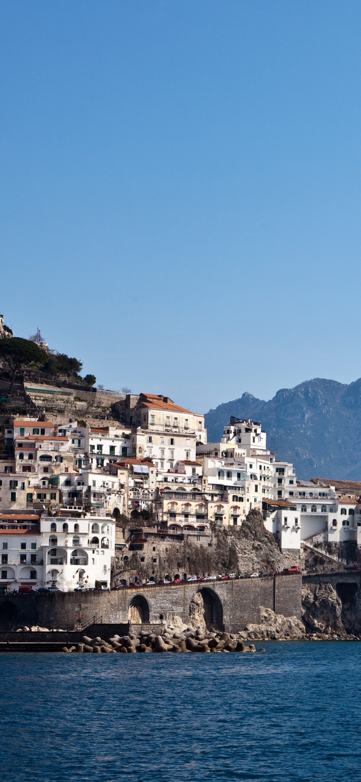 White and Brown Concrete Building Near Body of Water During Daytime. Wallpaper in 1242x2688 Resolution