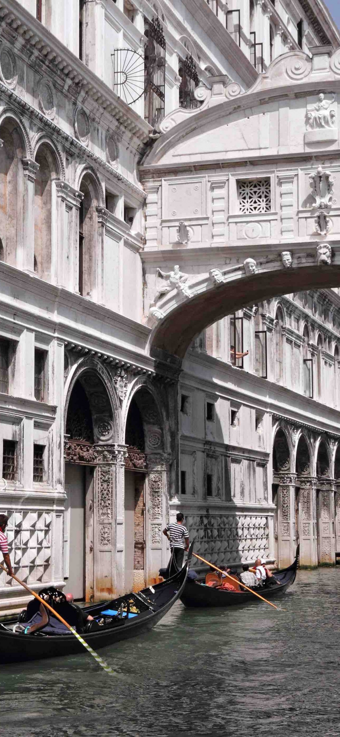 People Riding on Boat on River Near White Concrete Building During Daytime. Wallpaper in 1125x2436 Resolution