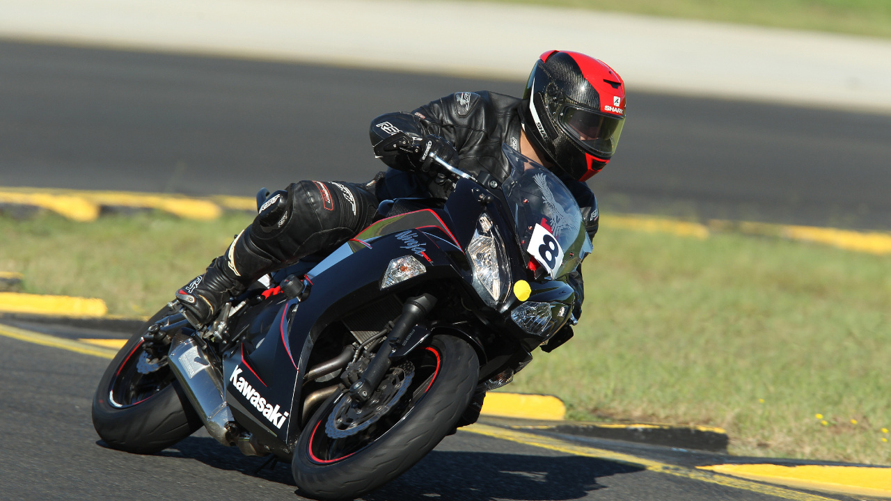 Man in Black and White Motorcycle Suit Riding on Black and White Sports Bike. Wallpaper in 1280x720 Resolution