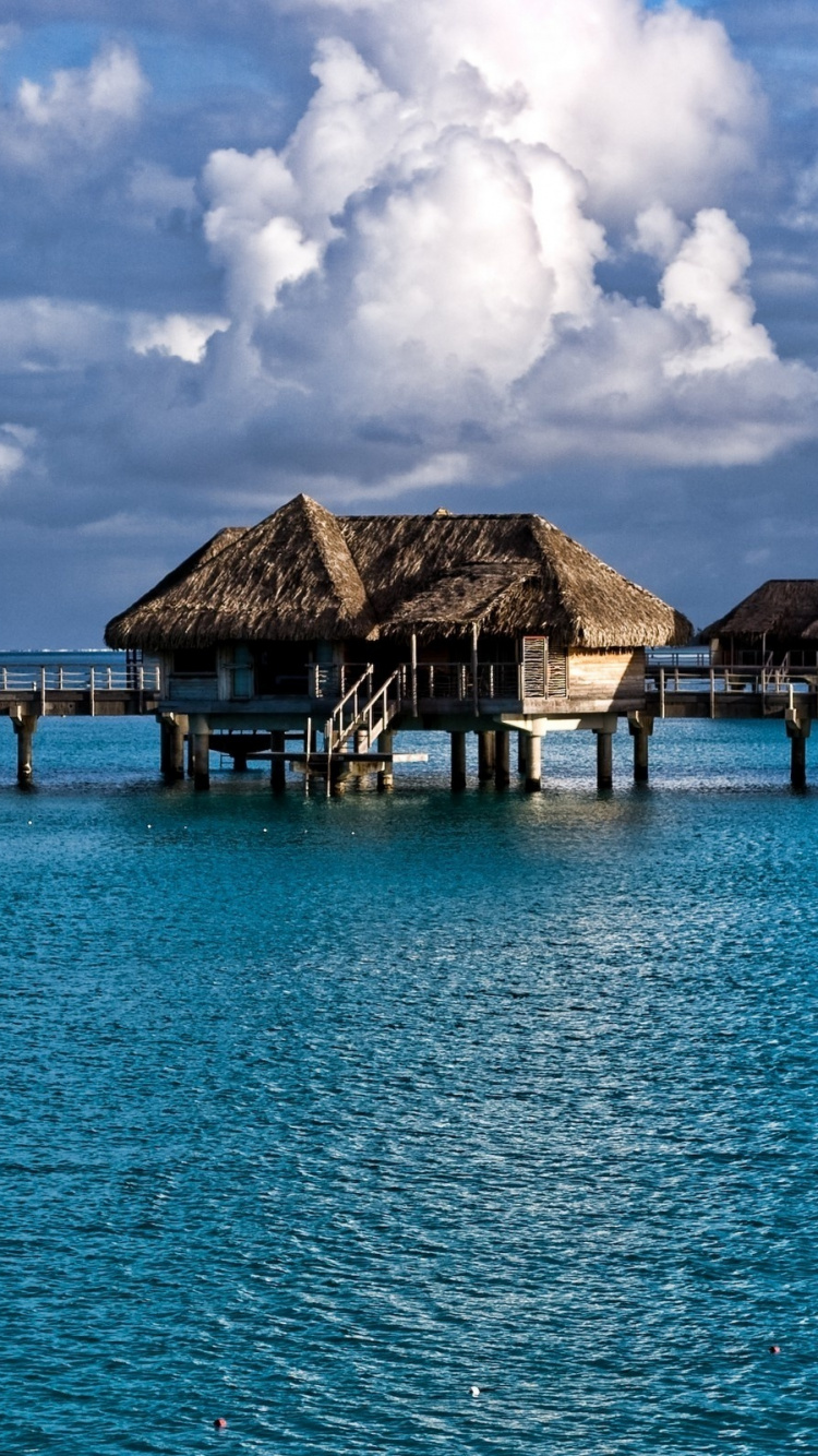 Casas de Madera Marrón en el Mar Azul Bajo un Cielo Azul Durante el Día. Wallpaper in 750x1334 Resolution