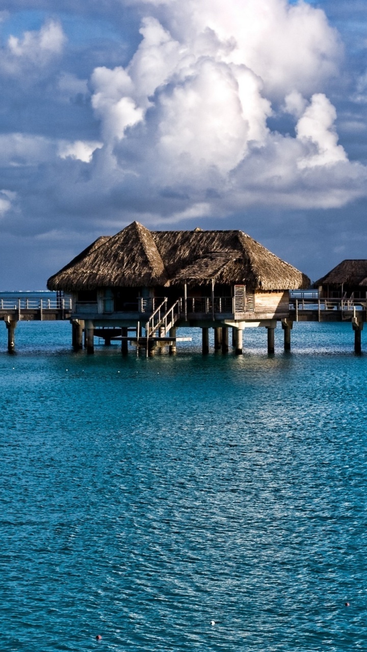 Brown Wooden Houses on Blue Sea Under Blue Sky During Daytime. Wallpaper in 720x1280 Resolution