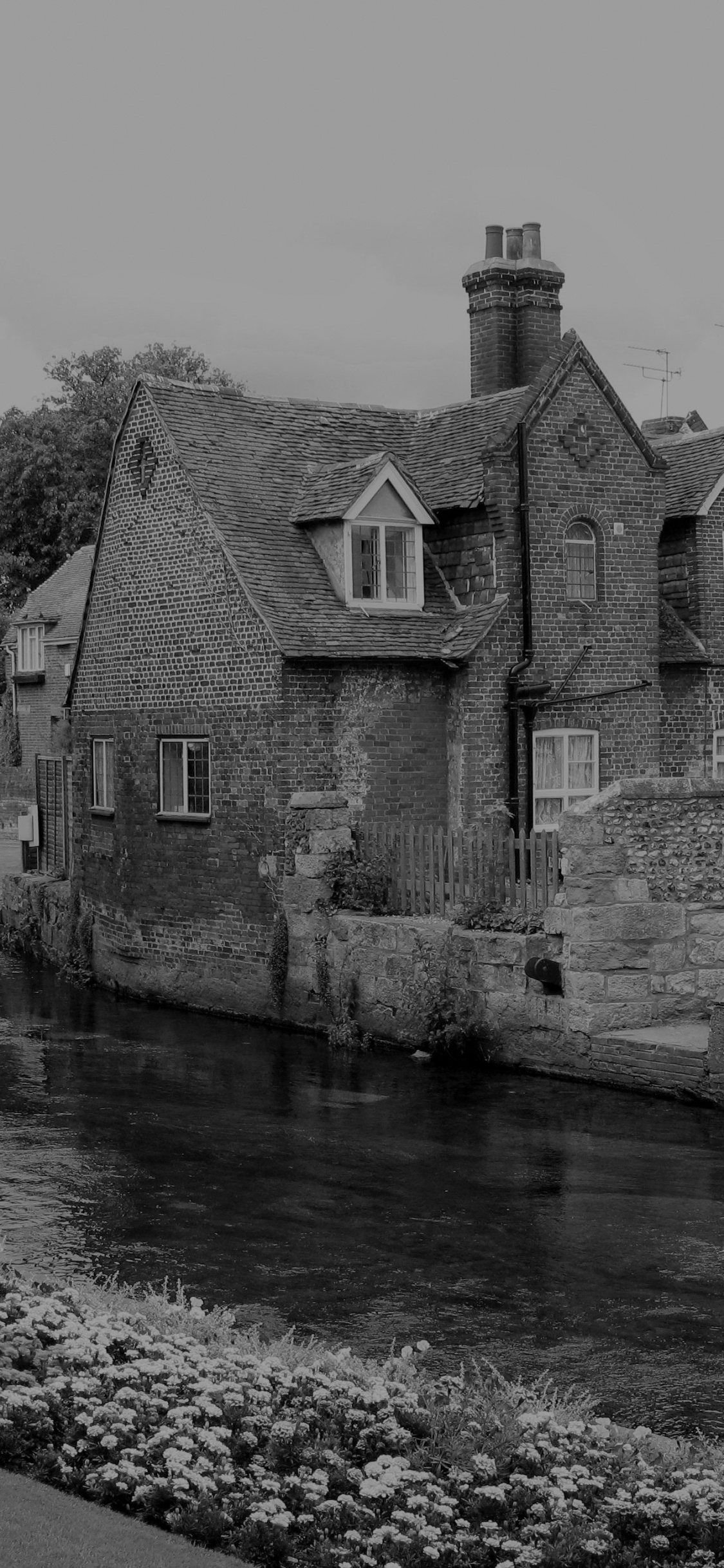 Grayscale Photo of Concrete House Near River. Wallpaper in 1125x2436 Resolution