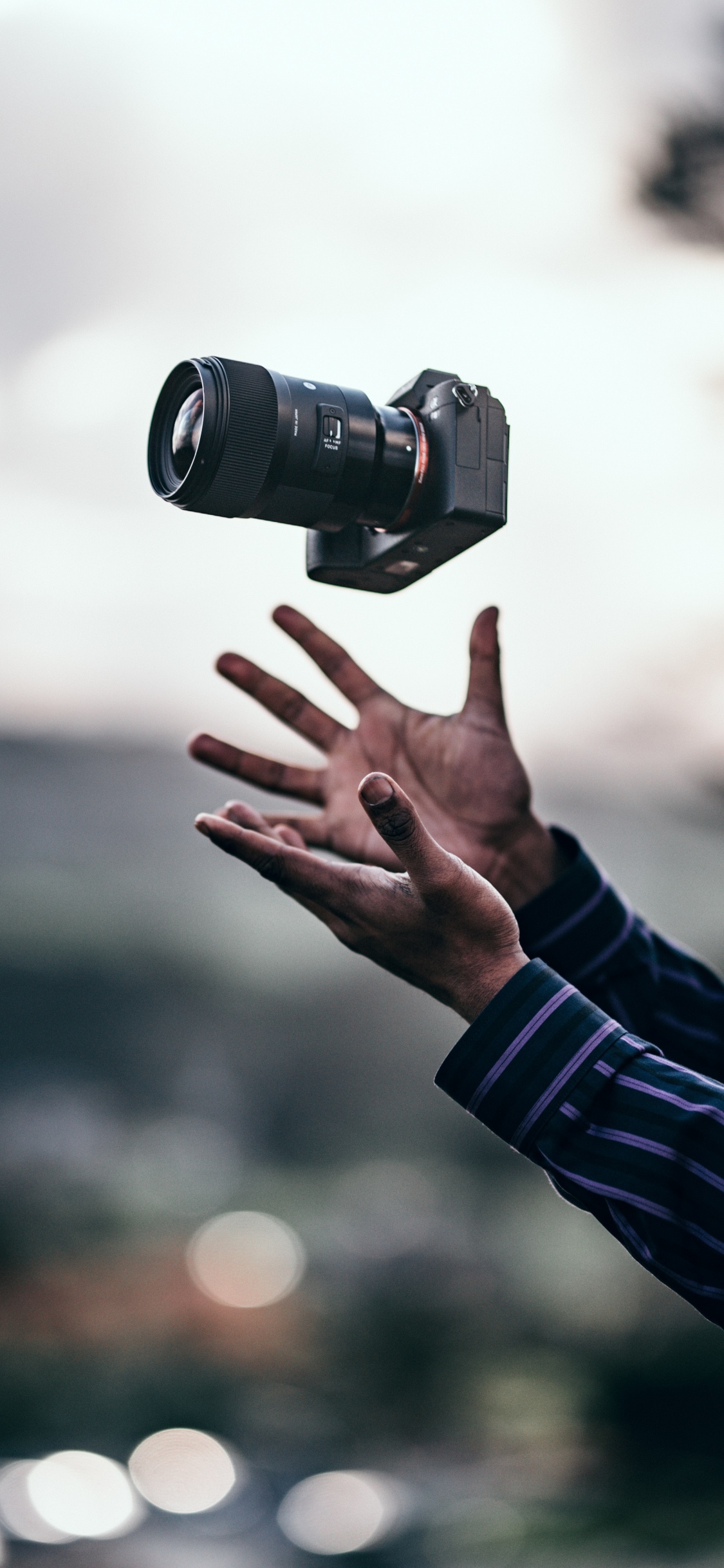 Person in Black Long Sleeve Shirt Holding Black Dslr Camera. Wallpaper in 1125x2436 Resolution