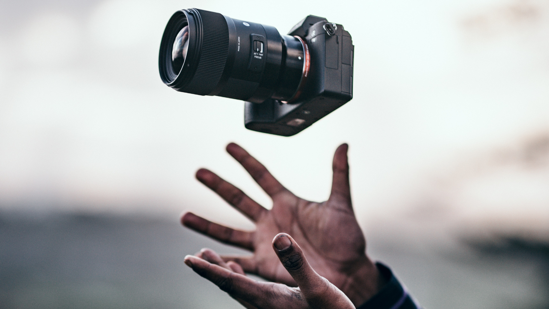 Person in Black Long Sleeve Shirt Holding Black Dslr Camera. Wallpaper in 1920x1080 Resolution