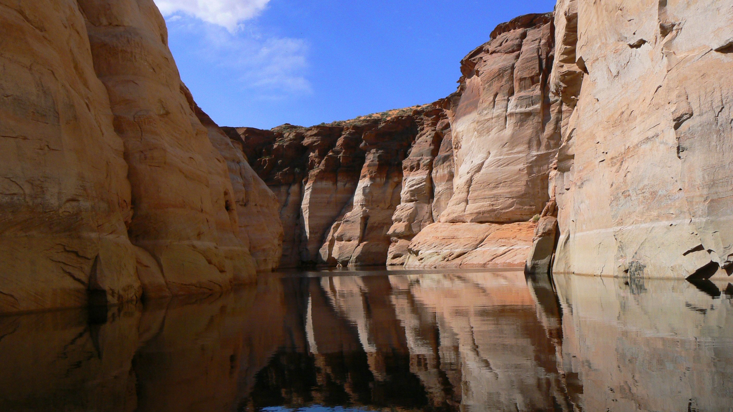 Formación de Roca Marrón Cerca Del Cuerpo de Agua Bajo un Cielo Azul Durante el Día. Wallpaper in 2560x1440 Resolution