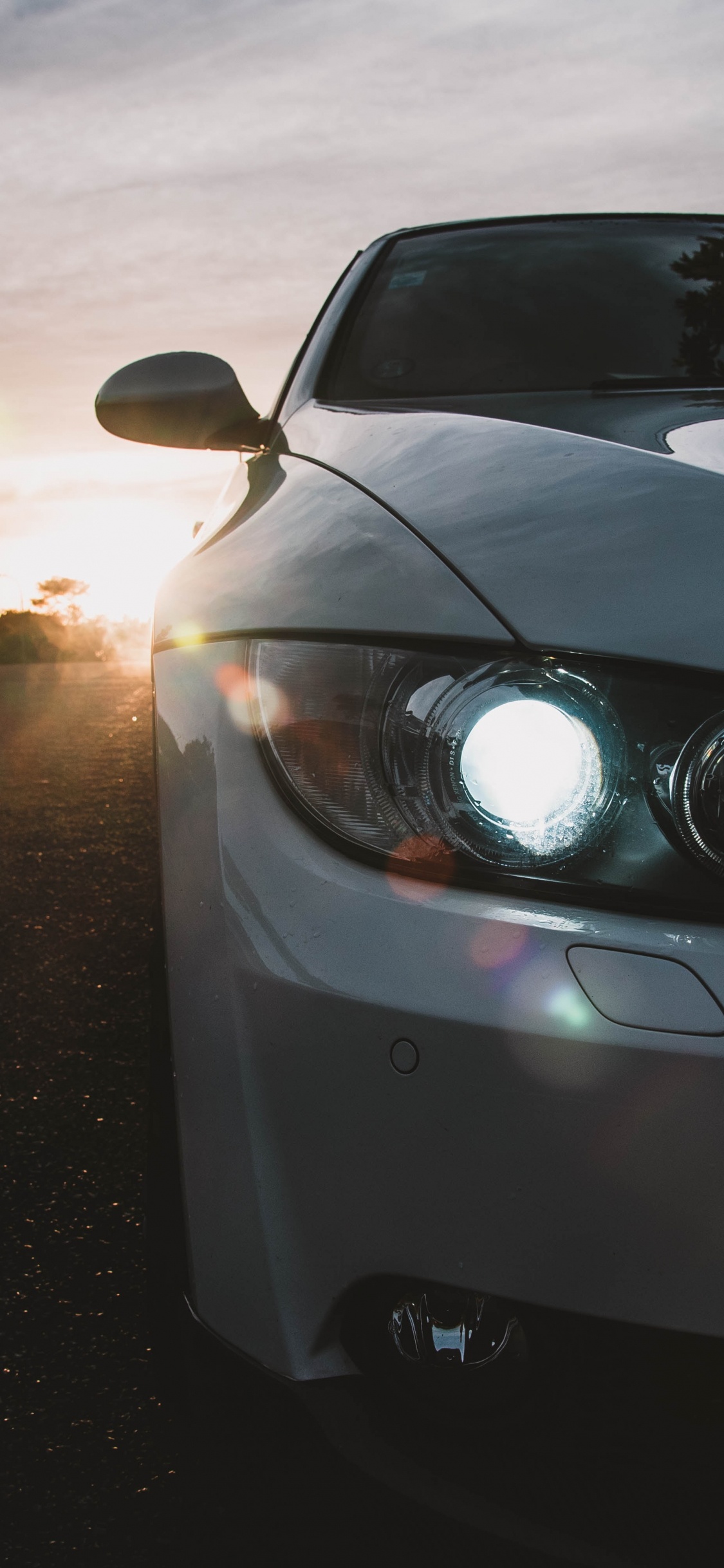 Graues Bmw-auto Auf Der Straße Bei Sonnenuntergang. Wallpaper in 1125x2436 Resolution