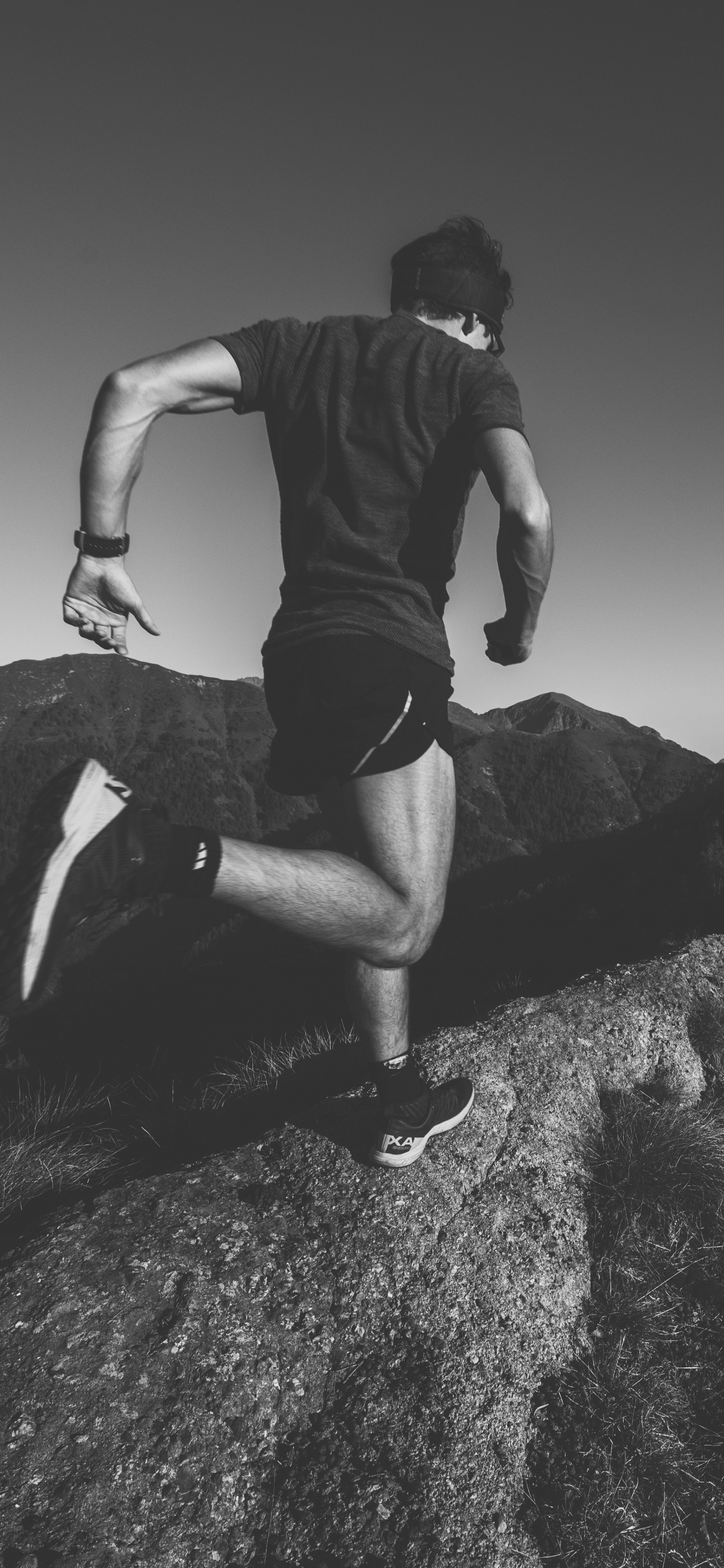 Man in Black T-shirt and Black Shorts Sitting on Rock. Wallpaper in 1242x2688 Resolution