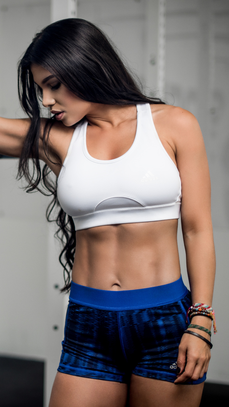 Femme en Soutien-gorge de Sport Blanc et Short Bleu Tenant Une Barre Noire. Wallpaper in 750x1334 Resolution
