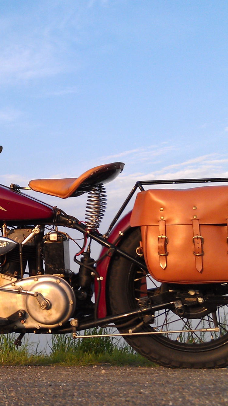 Orangefarbenes Und Schwarzes Motorrad Auf Grüner Wiese Unter Blauem Himmel Tagsüber. Wallpaper in 750x1334 Resolution