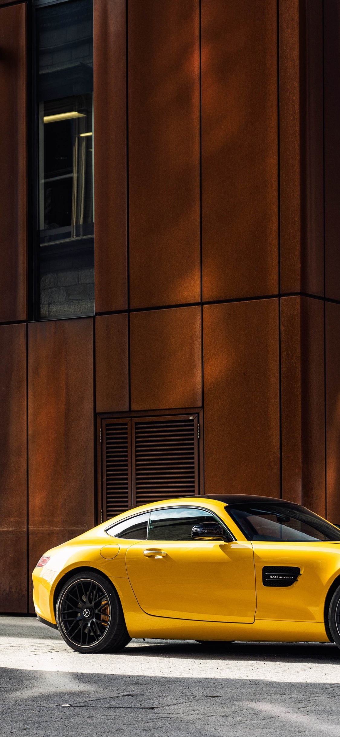 Gelber Porsche 911 Geparkt Neben Braunem Betongebäude Tagsüber. Wallpaper in 1125x2436 Resolution