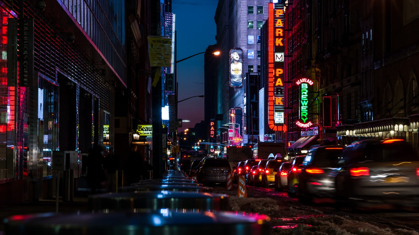 Autos Auf Der Straße Zwischen Hochhäusern Während Der Nacht. Wallpaper in 1366x768 Resolution