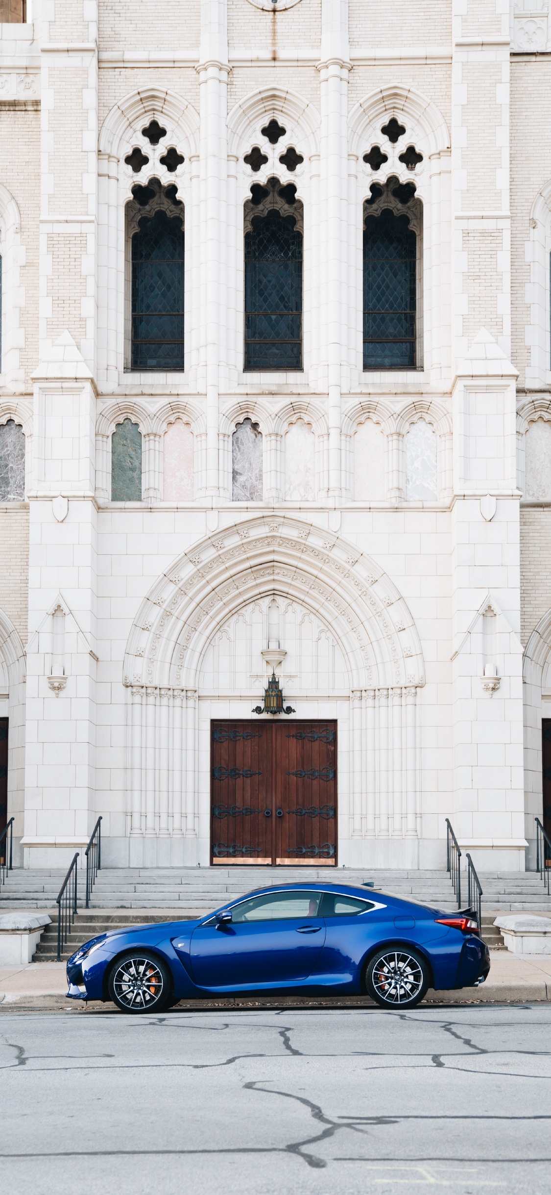 Coupé Bleu Garé à Côté D'un Bâtiment en Béton Blanc Pendant la Journée. Wallpaper in 1125x2436 Resolution