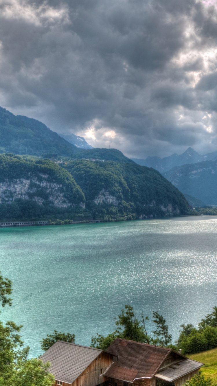 Brown Wooden House Near Green Trees and Body of Water Under Cloudy Sky During Daytime. Wallpaper in 750x1334 Resolution