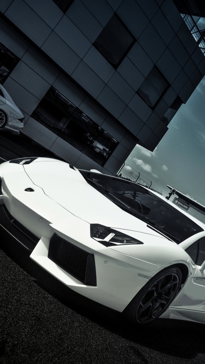 Lamborghini Aventador Blanco y Negro Estacionado Junto al Edificio Azul Durante el Día. Wallpaper in 720x1280 Resolution