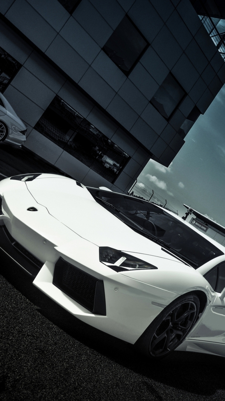 Lamborghini Aventador Blanche et Noire Garée à Côté du Bâtiment Bleu Pendant la Journée. Wallpaper in 750x1334 Resolution