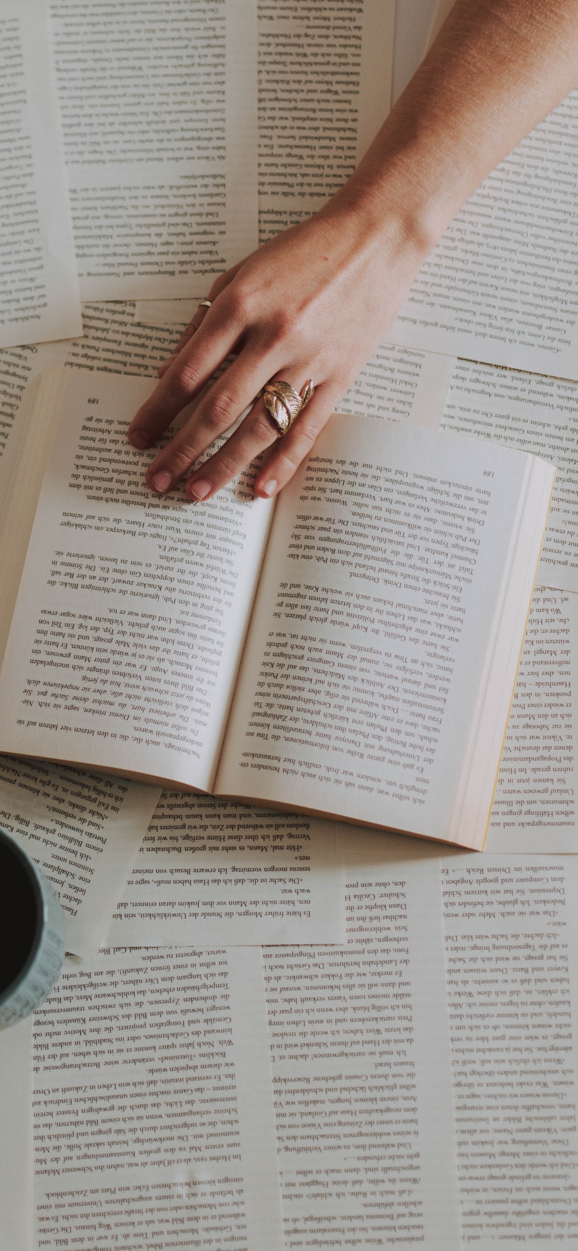 Person Holding White Ceramic Mug on White Book Page. Wallpaper in 1125x2436 Resolution