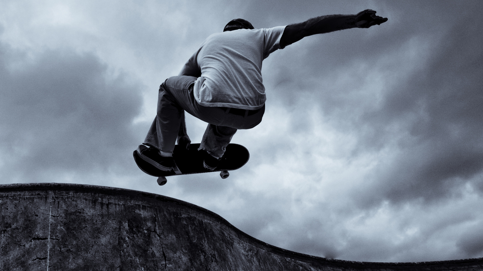 Man in Gray Hoodie and Black Pants Jumping on Gray Rock. Wallpaper in 1920x1080 Resolution