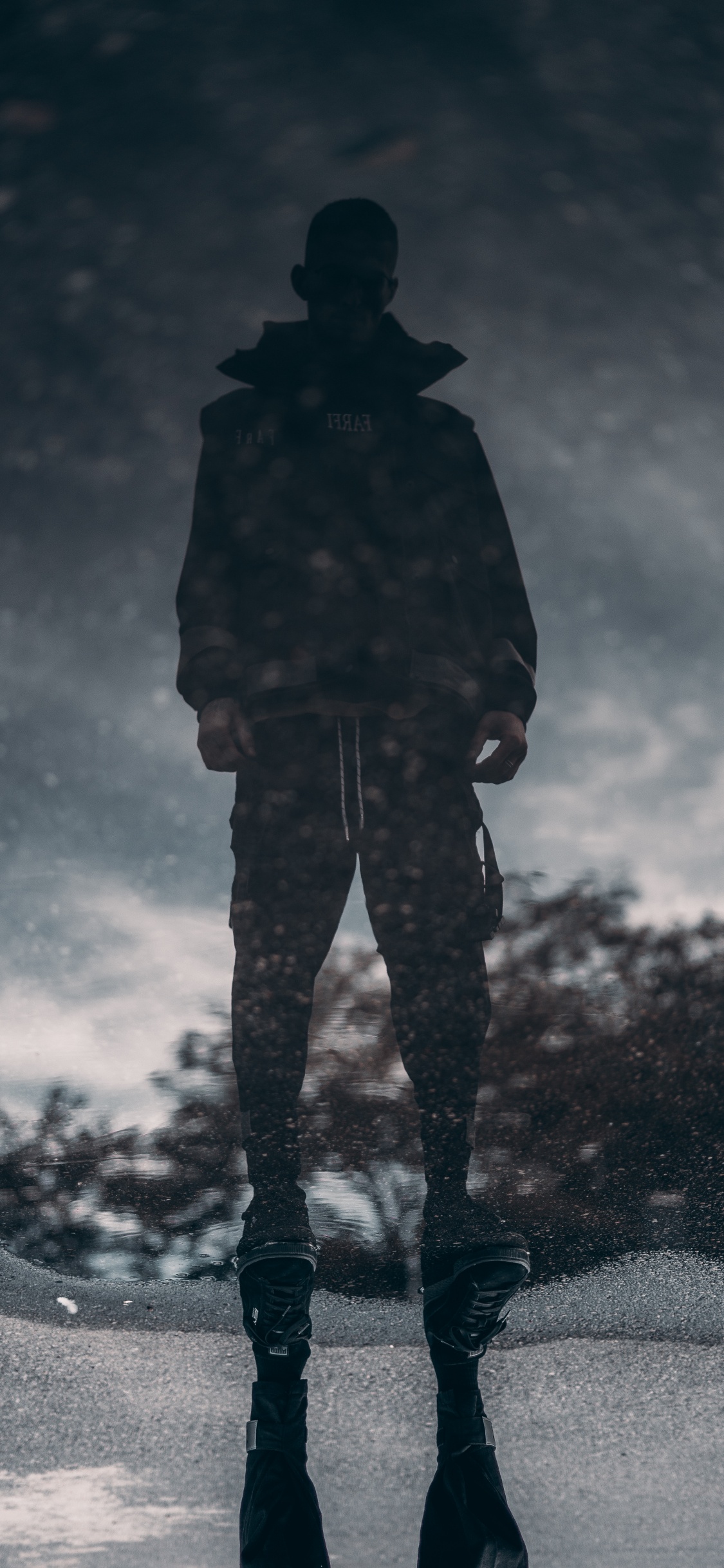 Man in Black Jacket and Pants Standing on Black and White Sky. Wallpaper in 1125x2436 Resolution