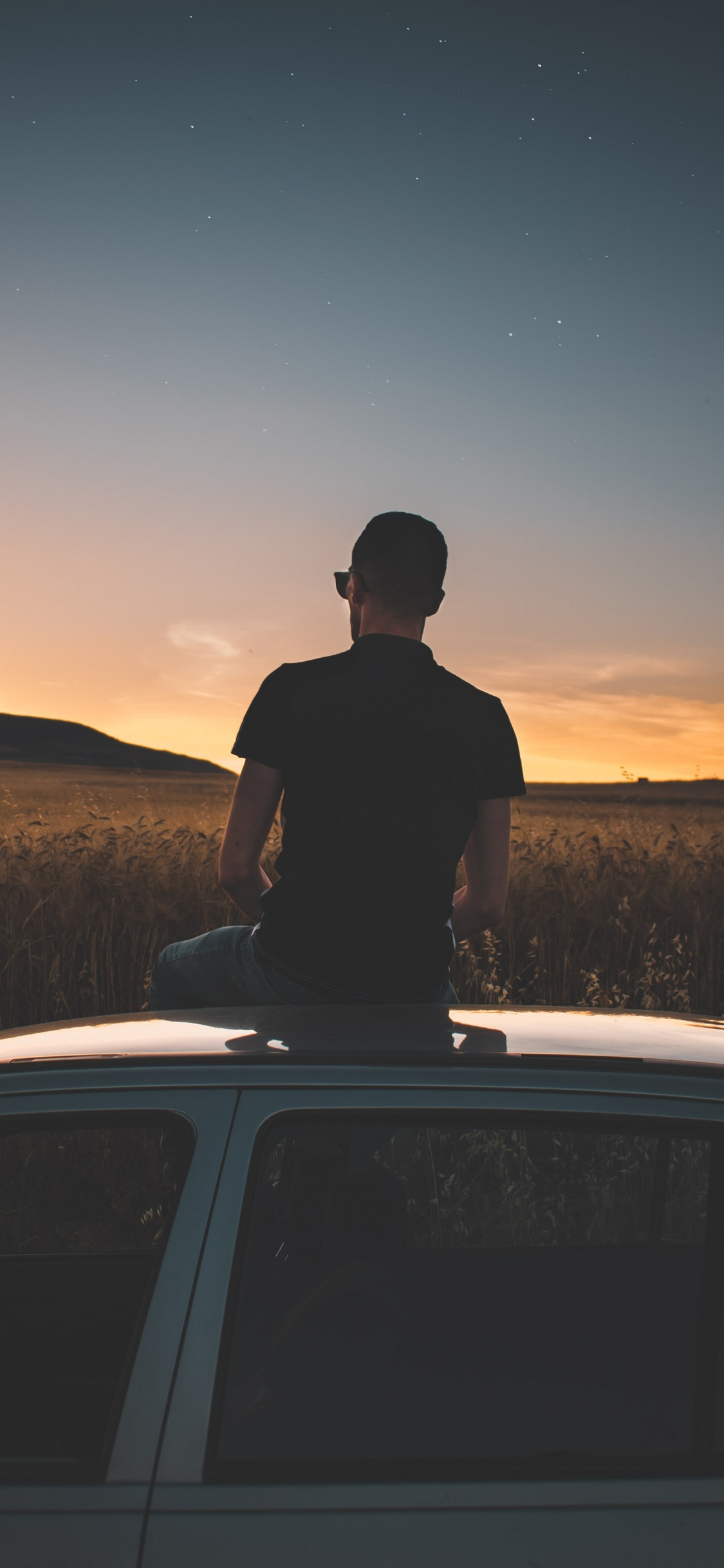 Silhouette of Man Standing on Car During Night Time. Wallpaper in 1125x2436 Resolution