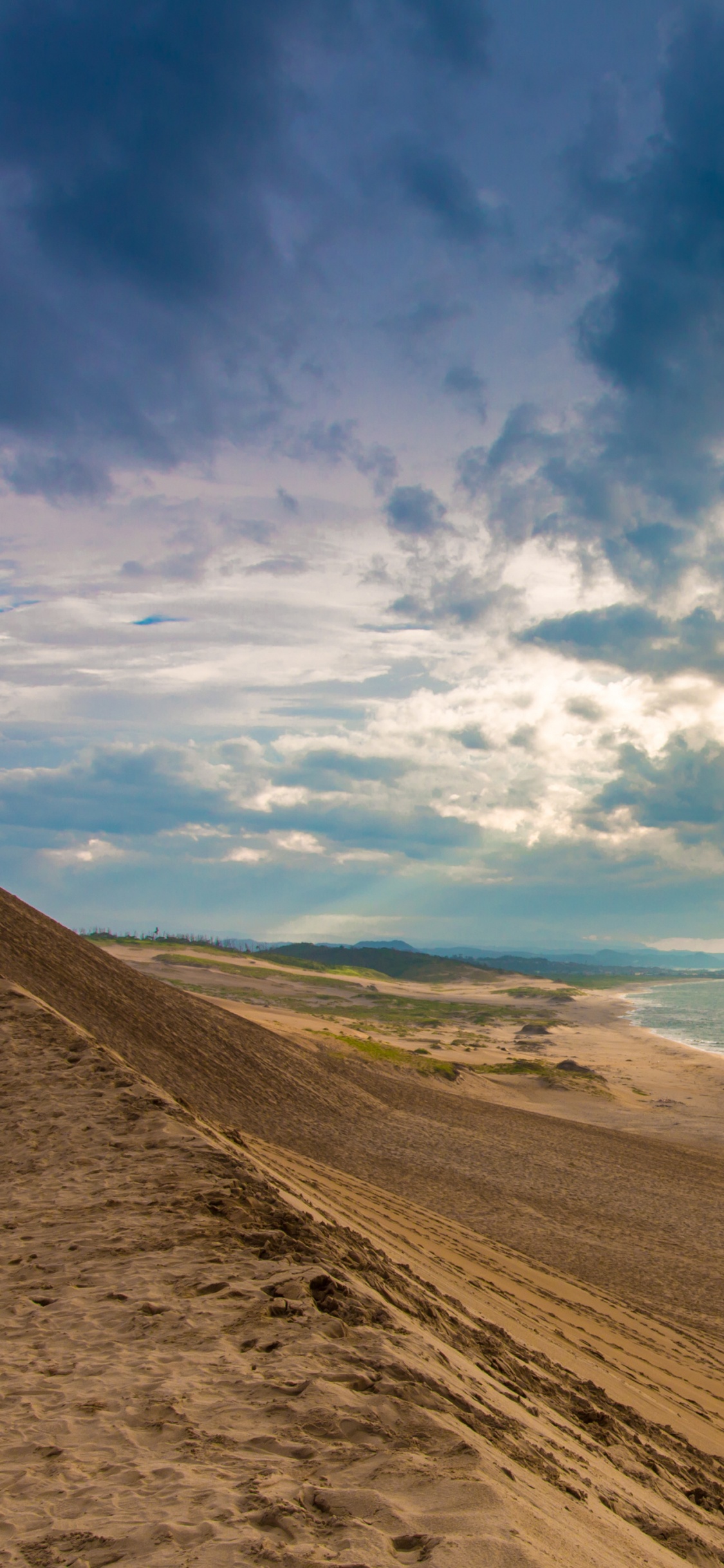Arena Marrón Cerca Del Cuerpo de Agua Bajo un Cielo Azul y Nubes Blancas Durante el Día. Wallpaper in 1125x2436 Resolution