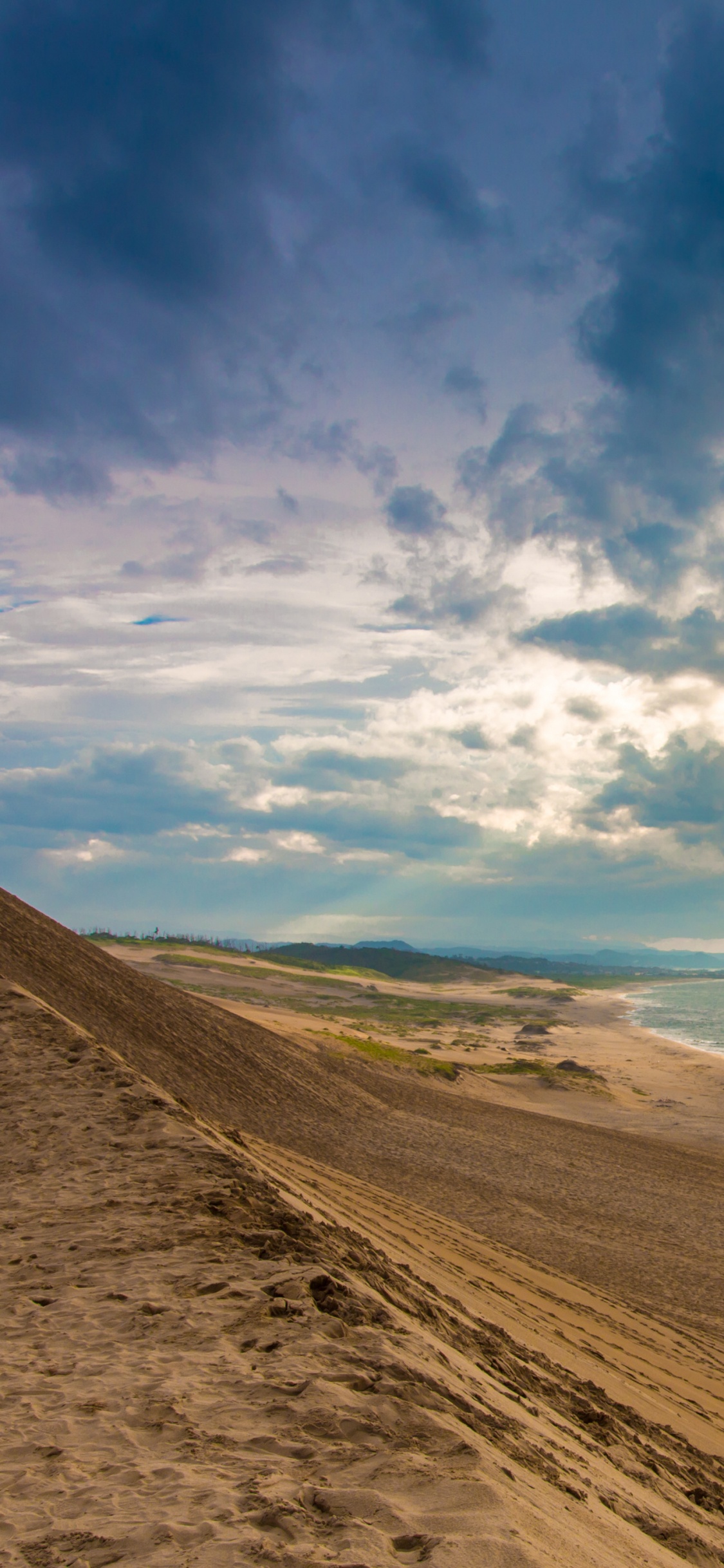 Brauner Sand in Der Nähe Von Gewässern Unter Blauem Himmel Und Weißen Wolken Tagsüber. Wallpaper in 1125x2436 Resolution